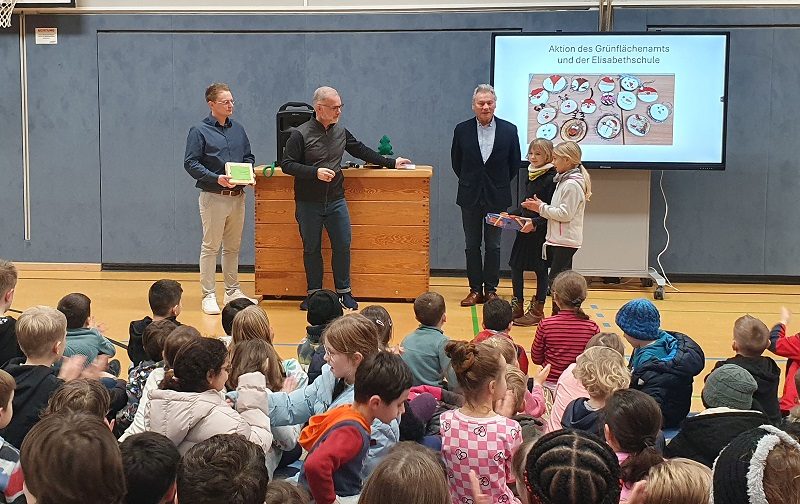 Die Schülersprecherinnen Clara Schulz und Mira Herkt überreichten Herrn Honervogt und Herrn Bieshold einige fertig gestellte Baumscheiben und erhielten Das „Bürgermeisterspiel“ der Stadt Paderborn.