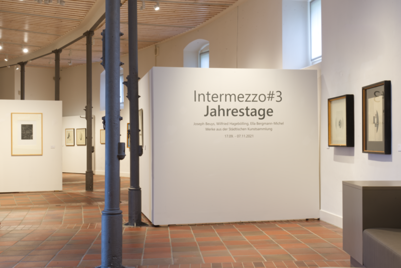 Ausstellungseingang zur Intermezzo#3 mit gerahmten Bildern an den weißen Wänden.