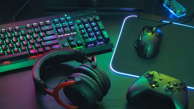 gamer work space concept, top view a gaming gear, mouse, keyboard, joystick, headset, mobile joystick, in ear headphone and mouse pad on black table background.