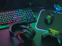 gamer work space concept, top view a gaming gear, mouse, keyboard, joystick, headset, mobile joystick, in ear headphone and mouse pad on black table background.